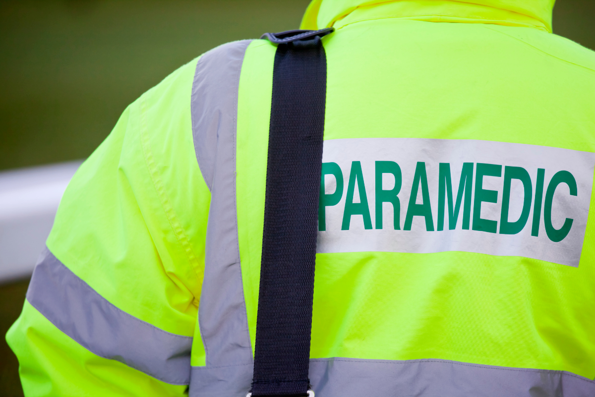 Photo of the back of a florescent yellow with green writing on a silver strip. The writing reads Paramedic. 